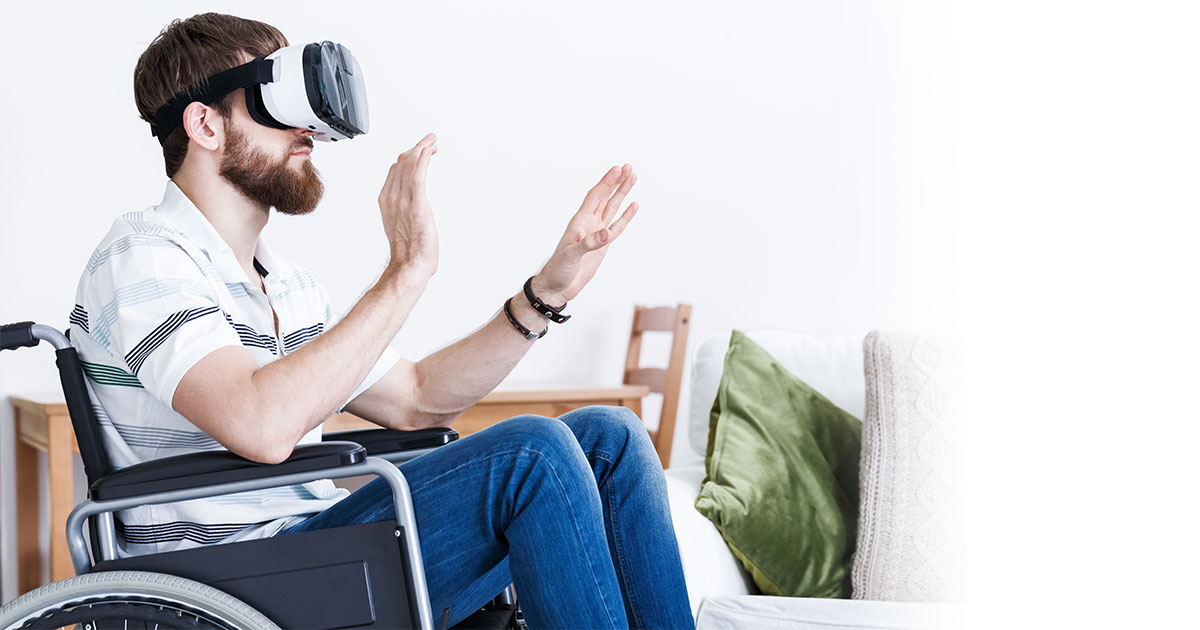 Mann im Rollstuhl trägt eine VR-Brille und interagiert mit virtuellen Inhalten.