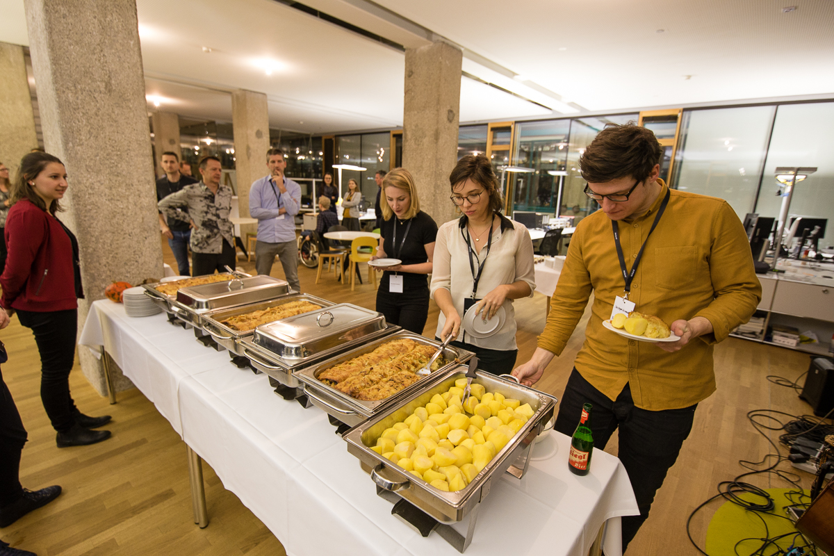 Mehrere Menschen stehen an einem Buffet und richten sich Teller.