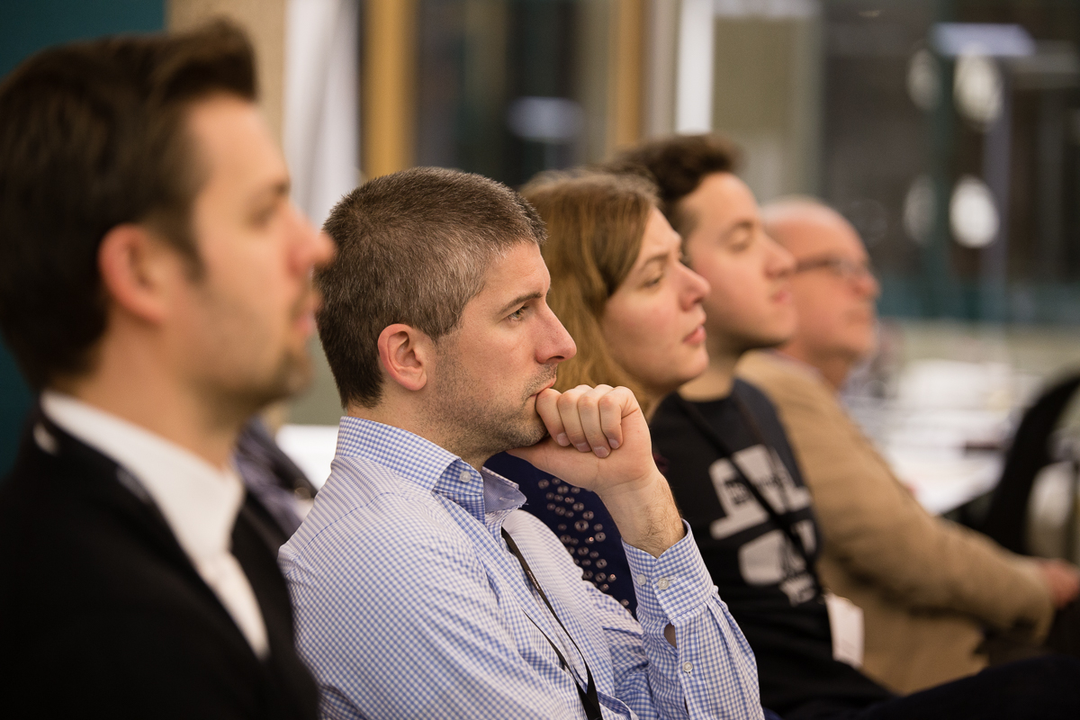 Mehrere Personen hören gespannt einem Redner zu.