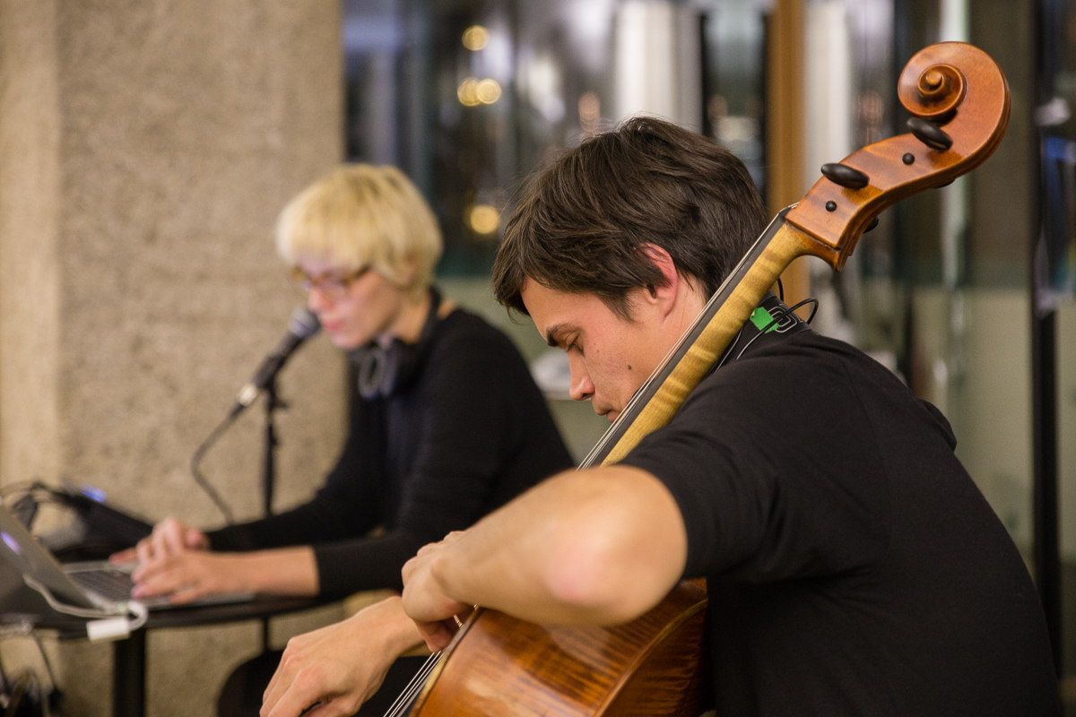 Ein Foto der Band, im Hintergrund verschwommen die Sängerin, im Vordergrund ist der Fokus auf den Cellospieler.