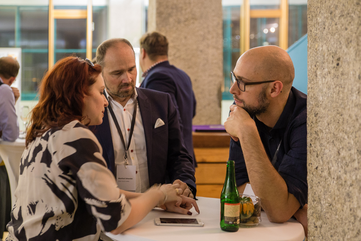 Drei Personen, eine Frau und zwei Männer, unterhalten sich gespannt.