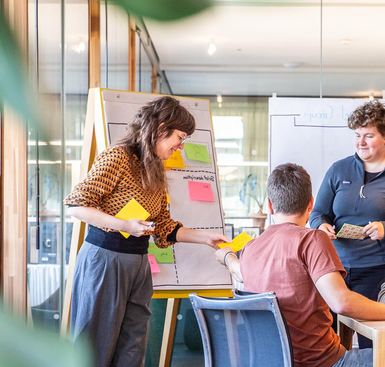 Ein Team arbeitet gemeinsam an einem Flipchart mit bunten Post-its in einem hellen Büro.
