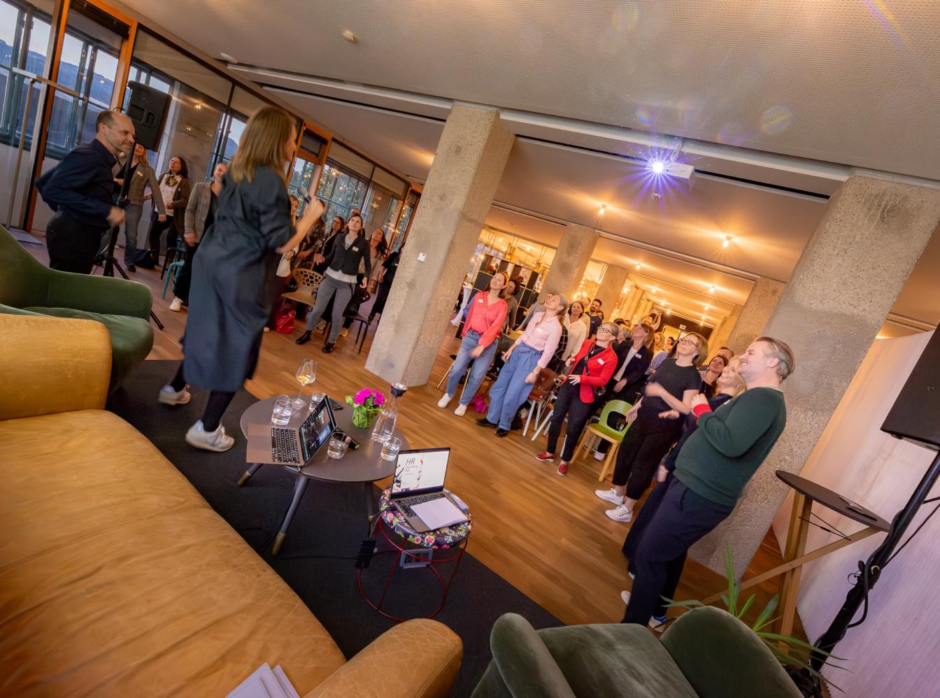 Gruppe bei einer interaktiven Session im modernen Netural-Büro mit Sofas und Projektor während der HR Coworking Night.