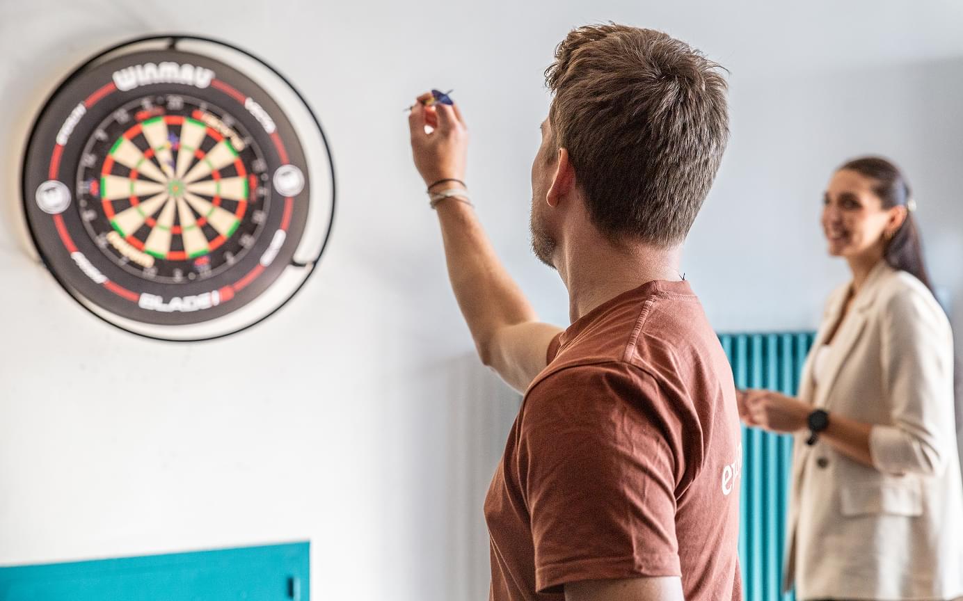 2 Kolleg:innen spielen gemeinsam Dart.