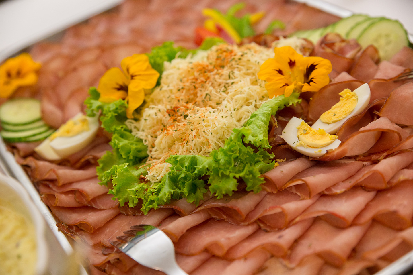 Detail shot of a platter with salad, ham, and hard-boiled eggs.