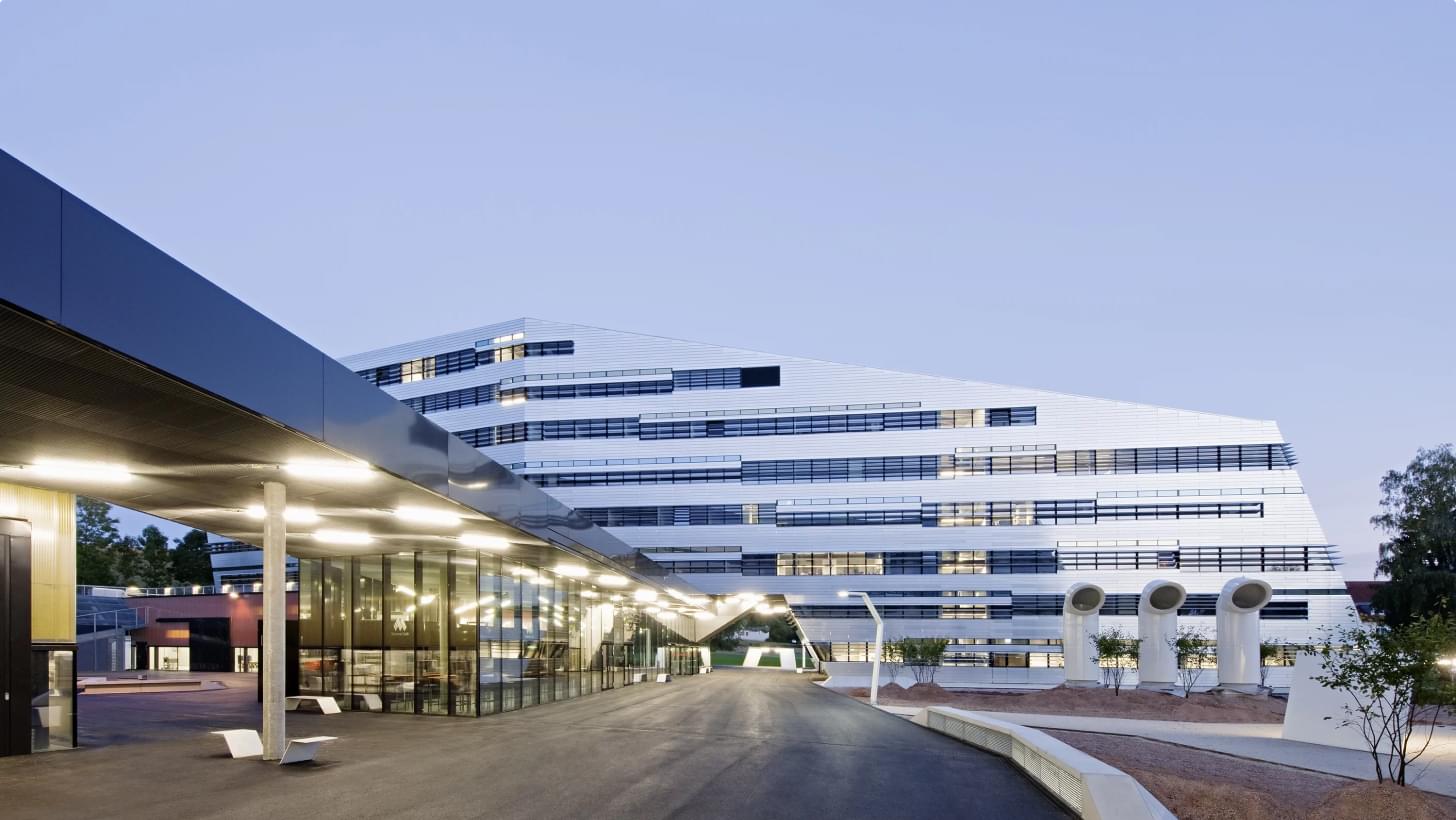 Exterior view of JKU Linz with modern architecture and glass facade at dusk.