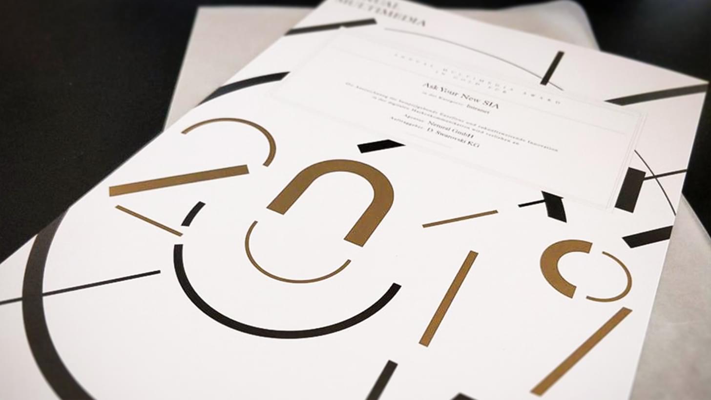 Annual Multimedia Award 2019 mit abstraktem schwarz-goldenem Design auf weißem Hintergrund.