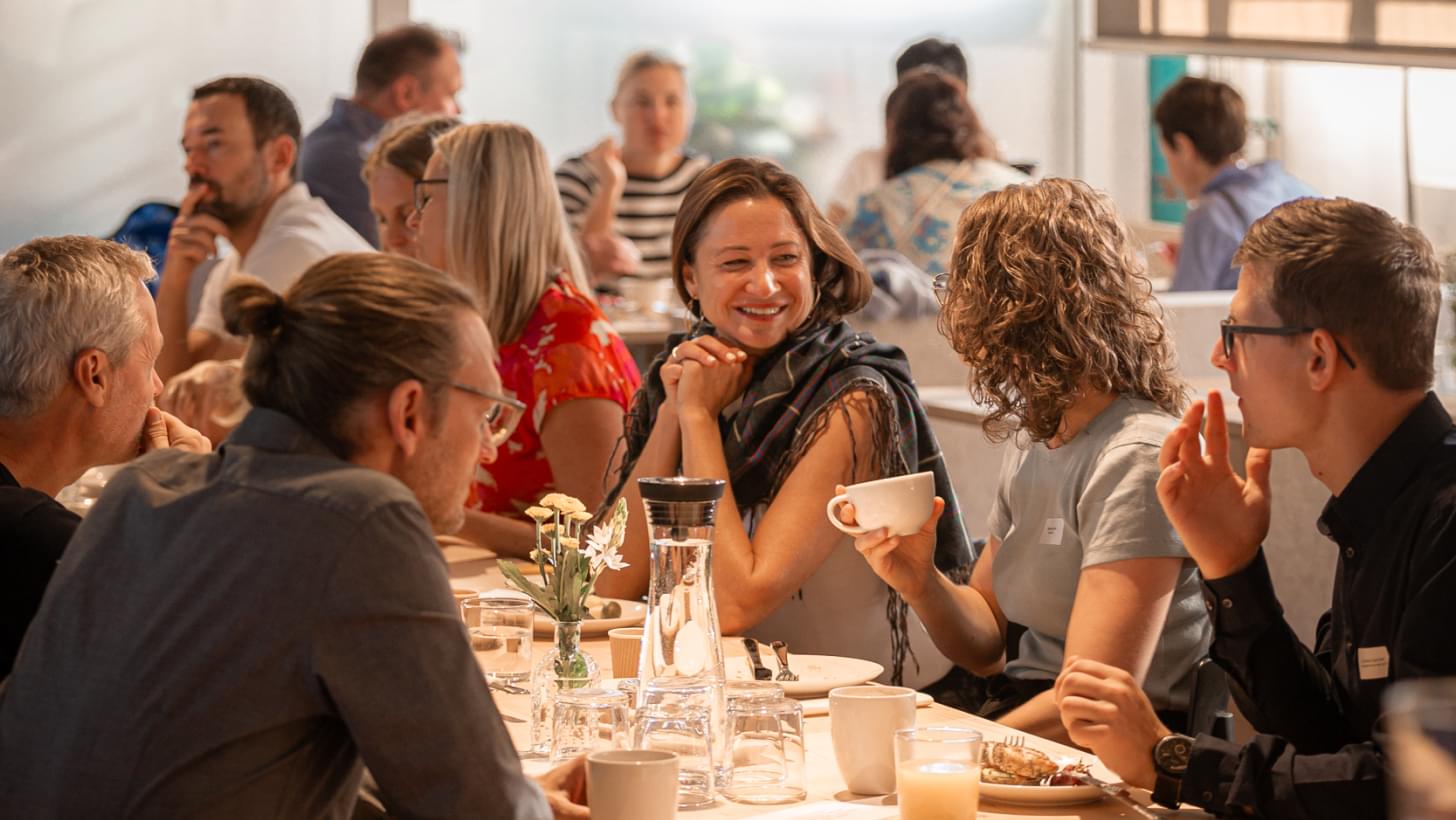 Participants at Netural’s “AI Impulse Breakfast” chatting over coffee at a shared table.