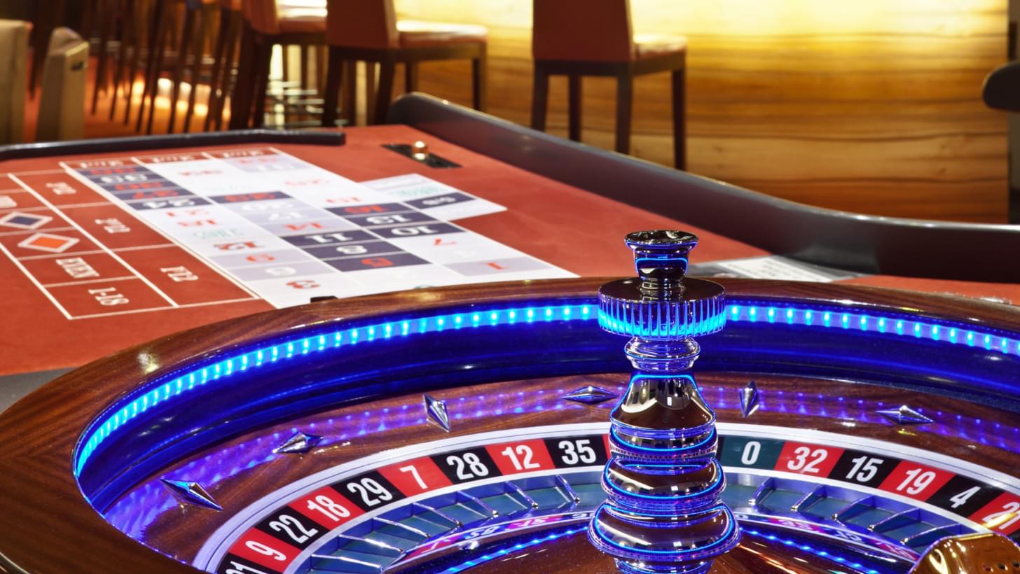 Detailansicht eines beleuchteten Roulette-Tisches und Spielbereichs in einem Casino.