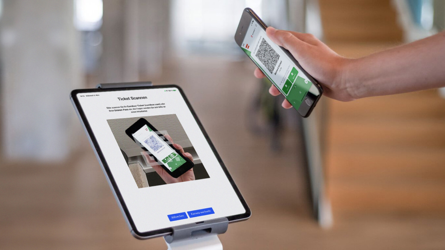 Hand holding smartphone with QR code in front of tablet running the Visidoor app for 2.5G access control.