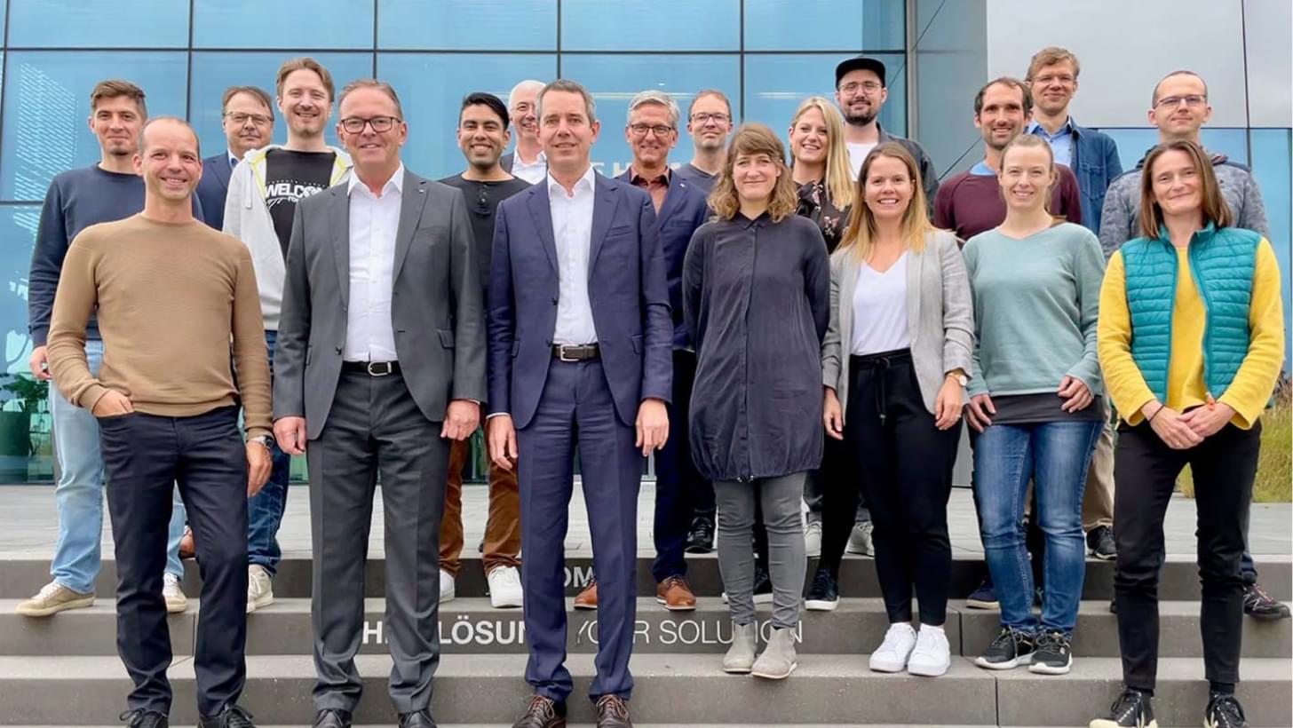 Albert Ortig, Ralf W. Dieter sowie das Führungsteam der Homag AG und Roomle-Team auf einer Treppe vor dem Gebäude.
