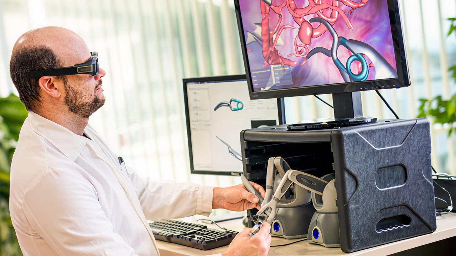Man in a white coat operating a surgical simulation system with 3D glasses at a computer.