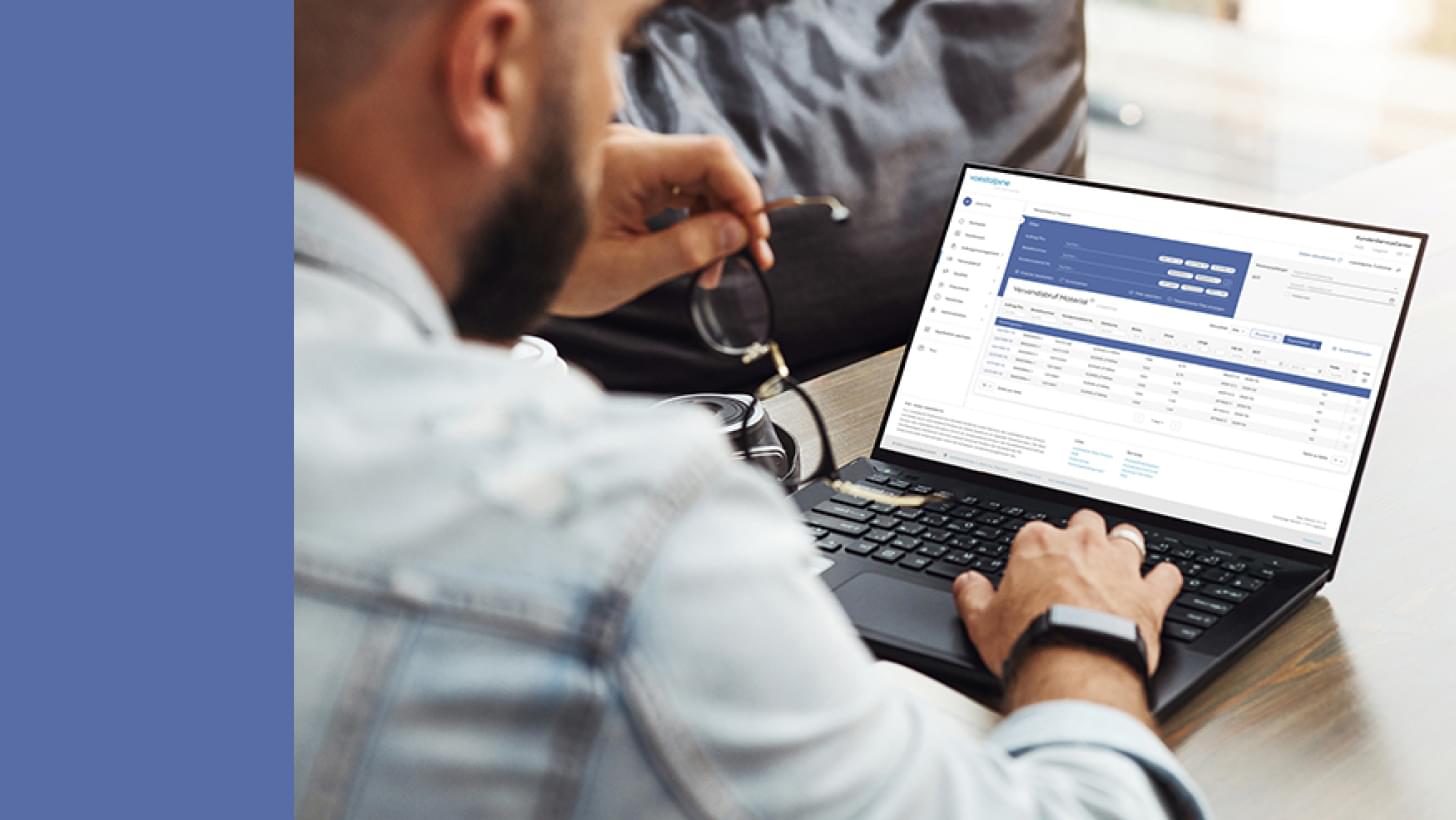 Ein Mann arbeitet an einem Laptop mit geöffnetem Dashboard und hält dabei seine Brille in der Hand.