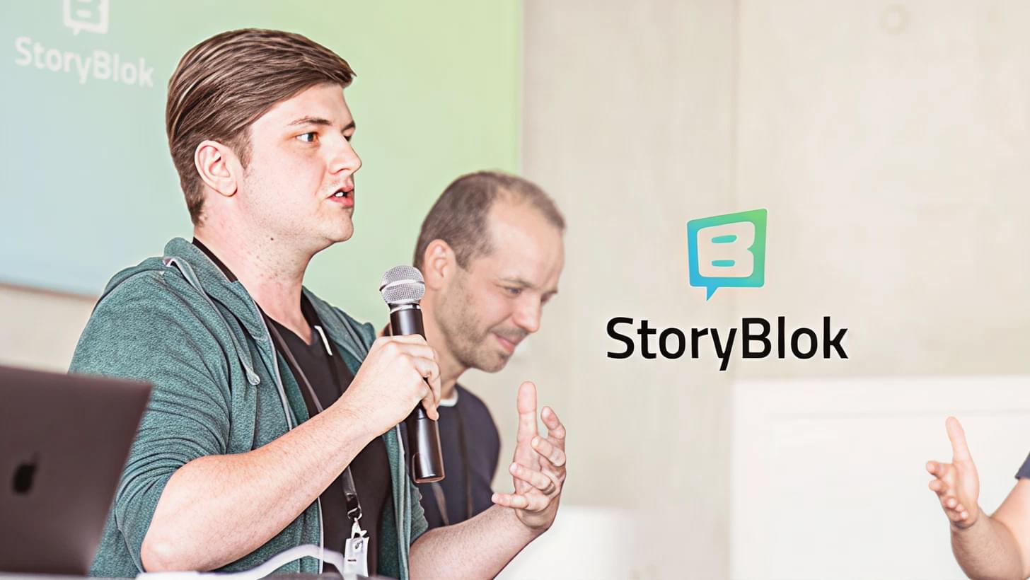 Dominik Angerer (CEO Storyblok) spricht vor einer Leinwand über Storyblok, im Hintergrund steht Albert Ortig (CEO Netural).