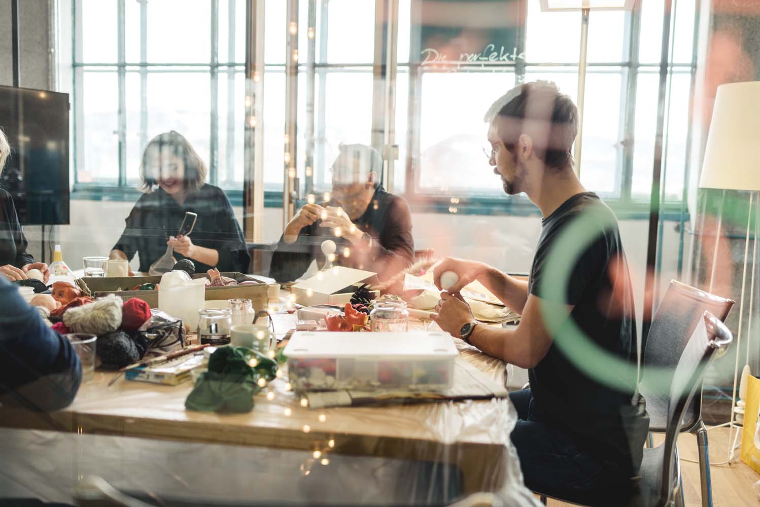Mehrere Personen arbeiten gemeinsam an Bastelprojekten an einem großen Tisch.
