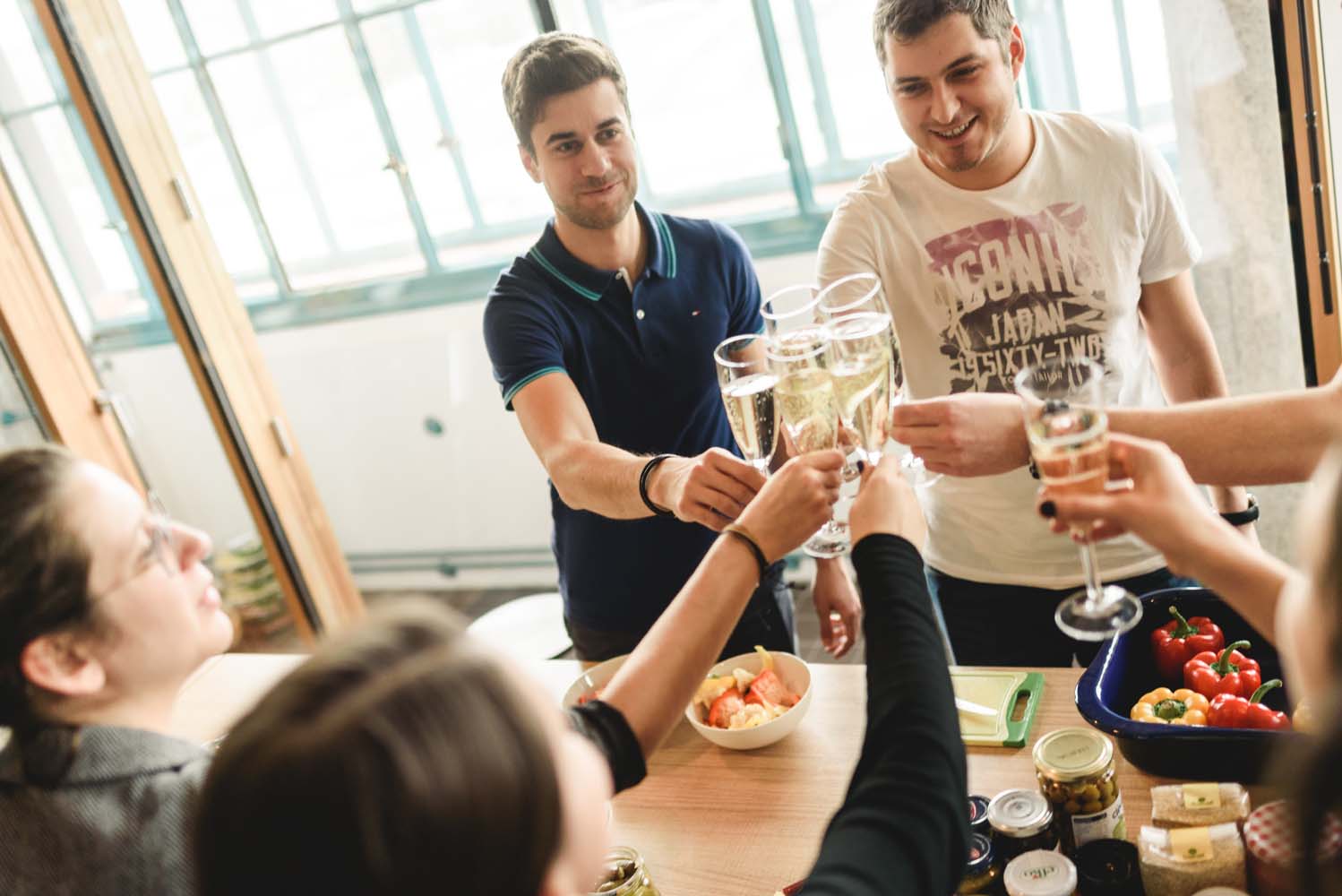 Gruppe von Personen stößt mit Sektgläsern im Büro an.