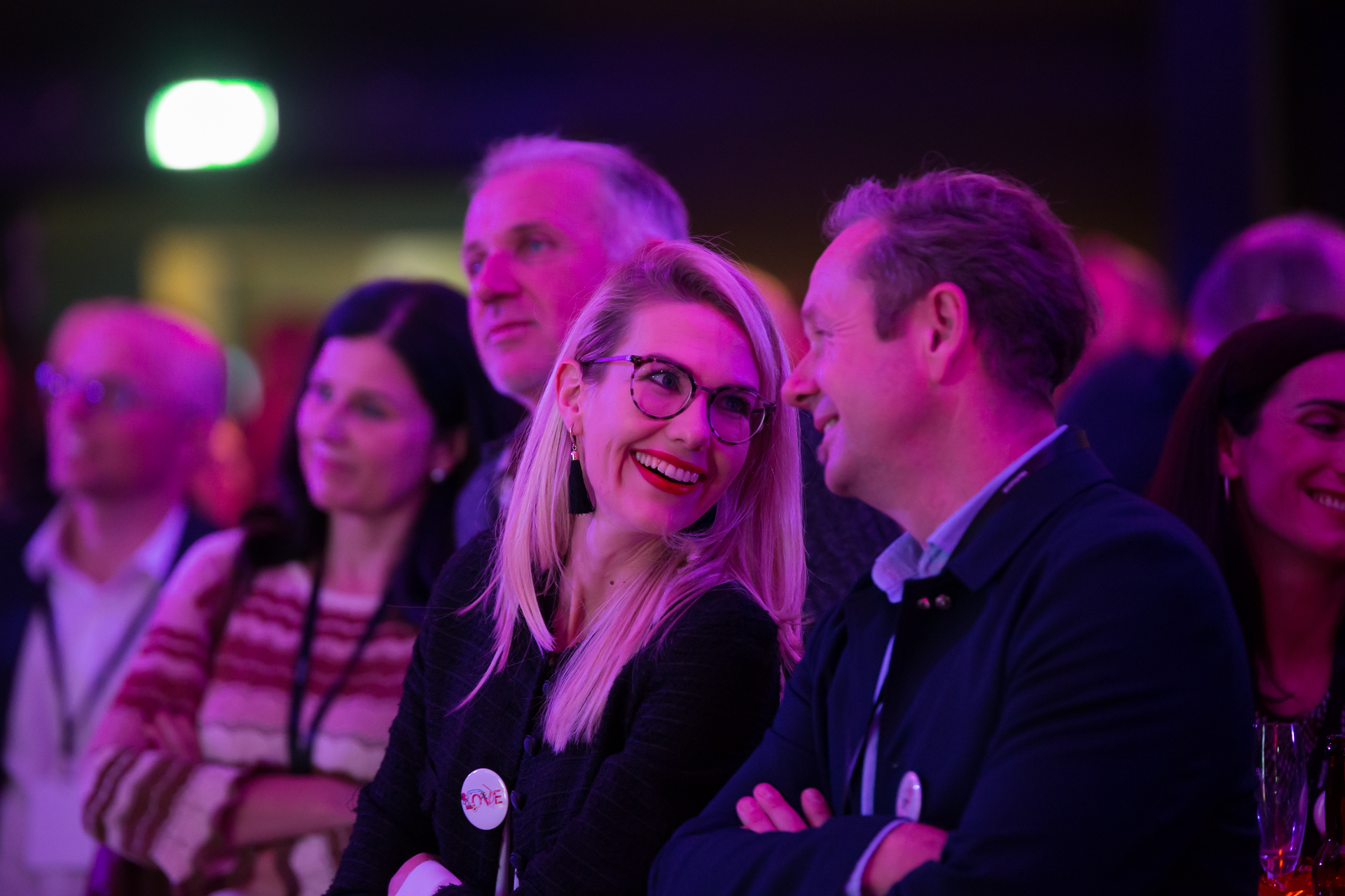 Group of people at an event, a woman laughs at another person.