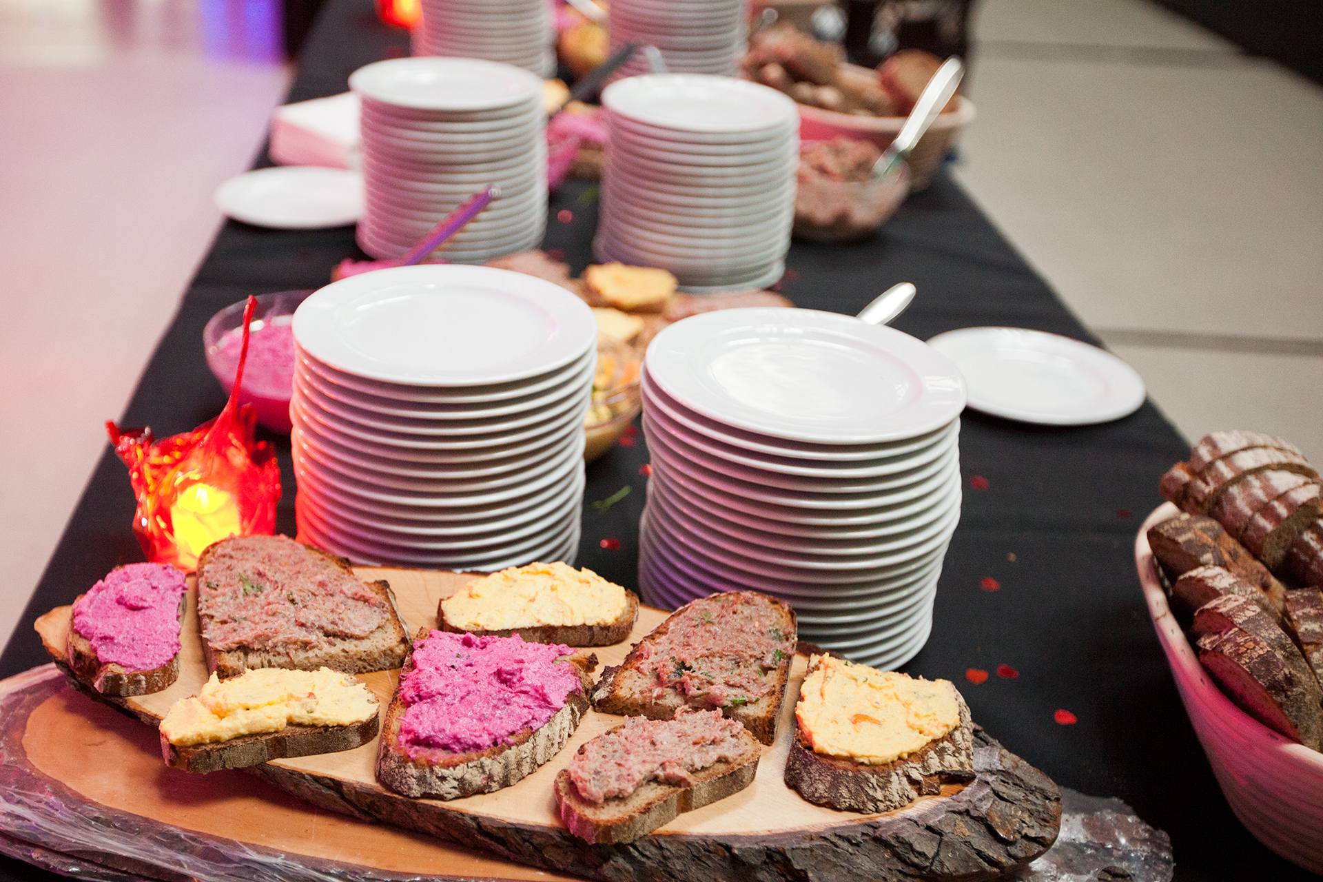Plate with breads, spread with various toppings, in front of a stack of plates at the buffet.