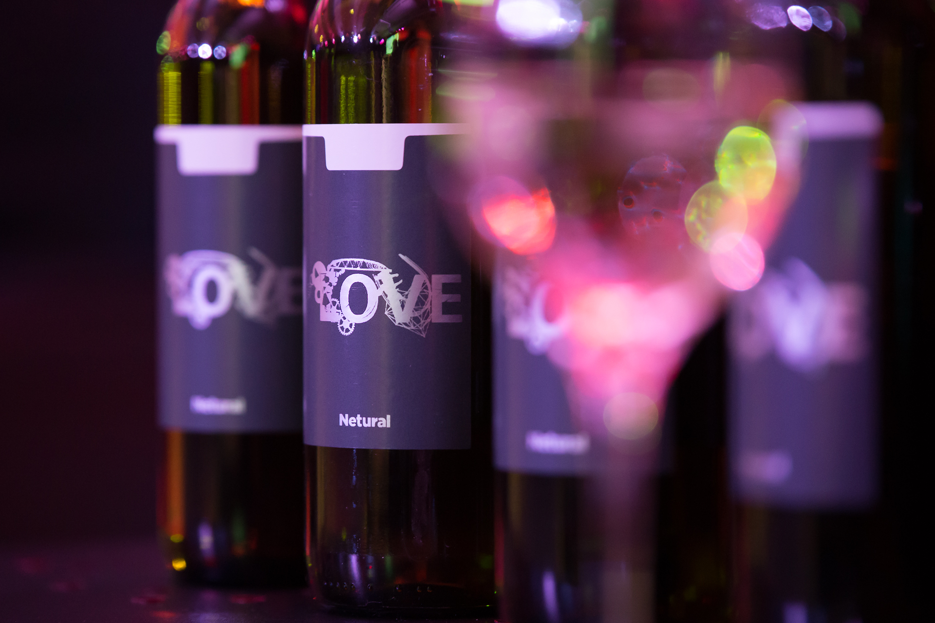 Several bottles with Netural's LOVE label, with a wine glass in the foreground.