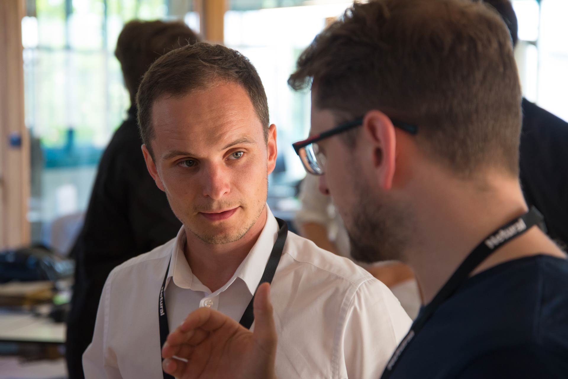 Close-up of two men having a conversation, with the man in focus listening attentively.