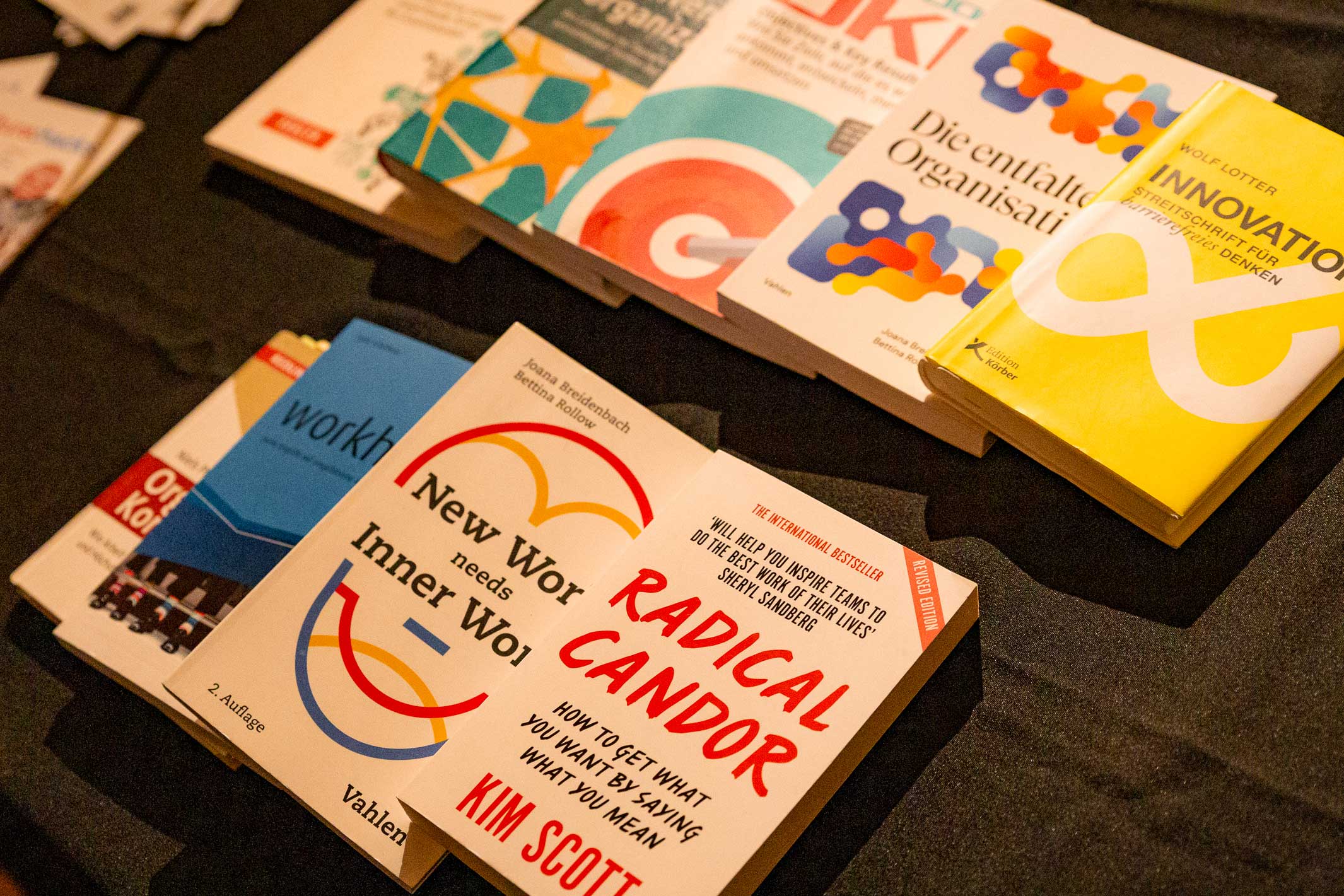 Auswahl an Büchern zu Innovation, Organisation und Führung auf einem schwarzen Tisch arrangiert.