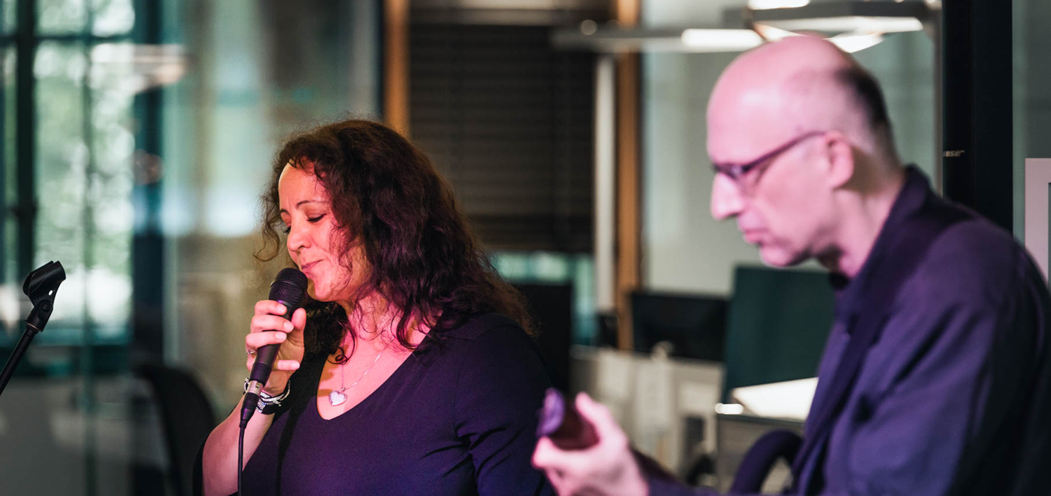 Sängerin mit Mikrofon und Gitarrist bei einem Live-Auftritt – musikalischer Ausklang der Veranstaltung.