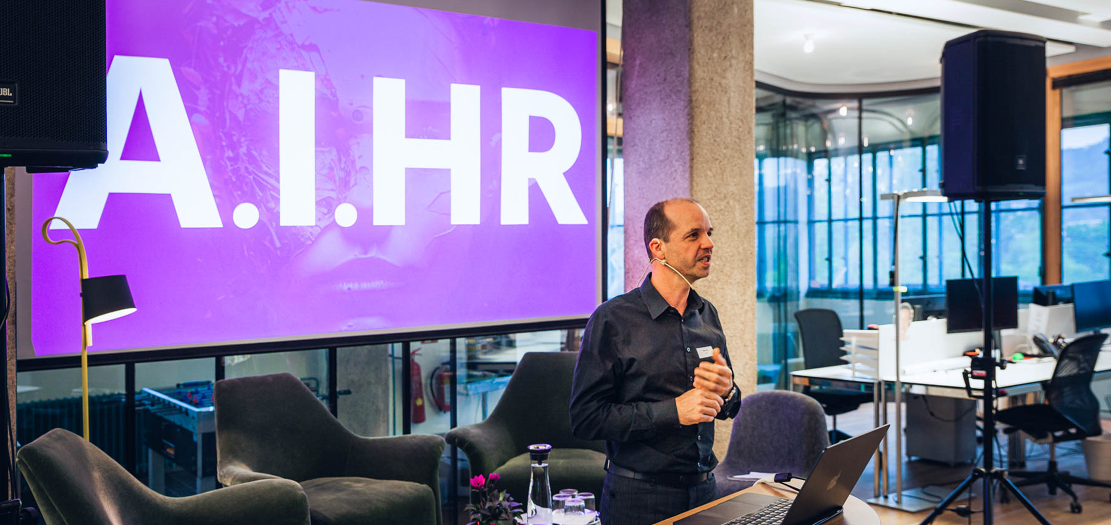 Albert Ortig spricht mit Headset vor der Folie „A.I.HR“ über künstliche Intelligenz im HR-Bereich.