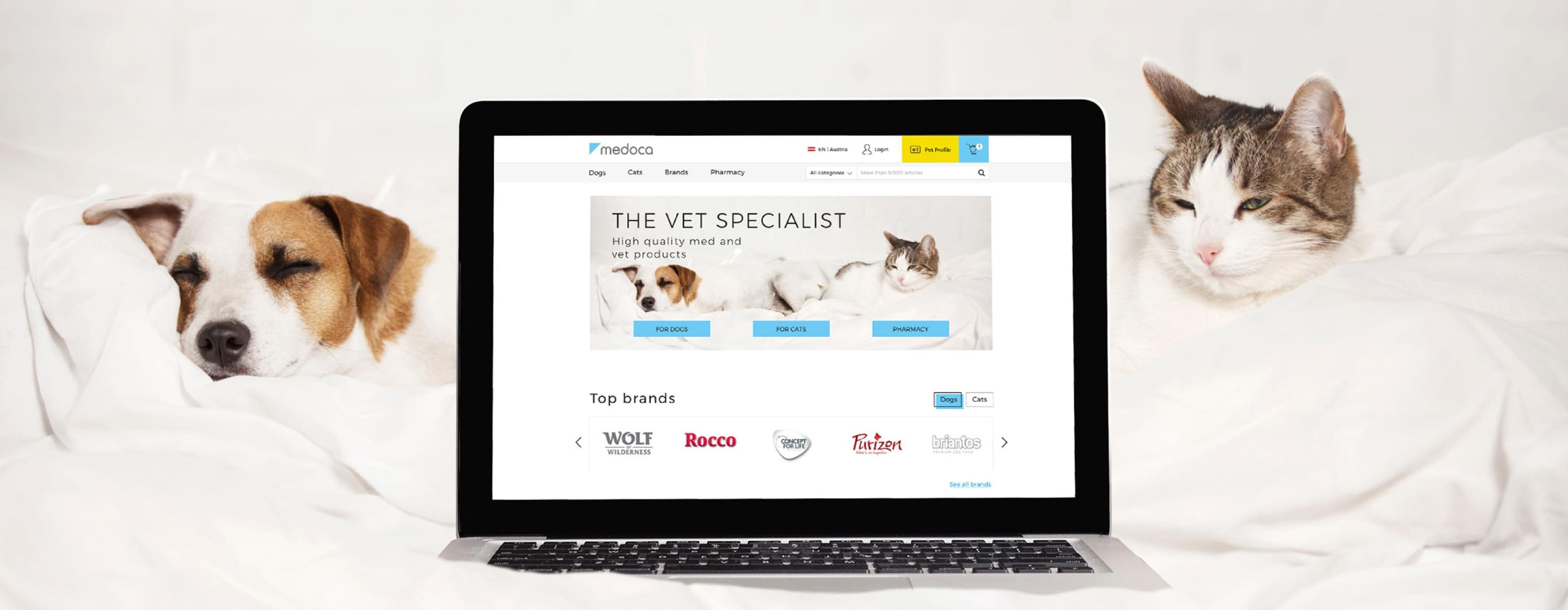 Laptop zeigt die Medoca-Startseite mit Hund und Katze, platziert zwischen einem echten Hund und einer Katze.