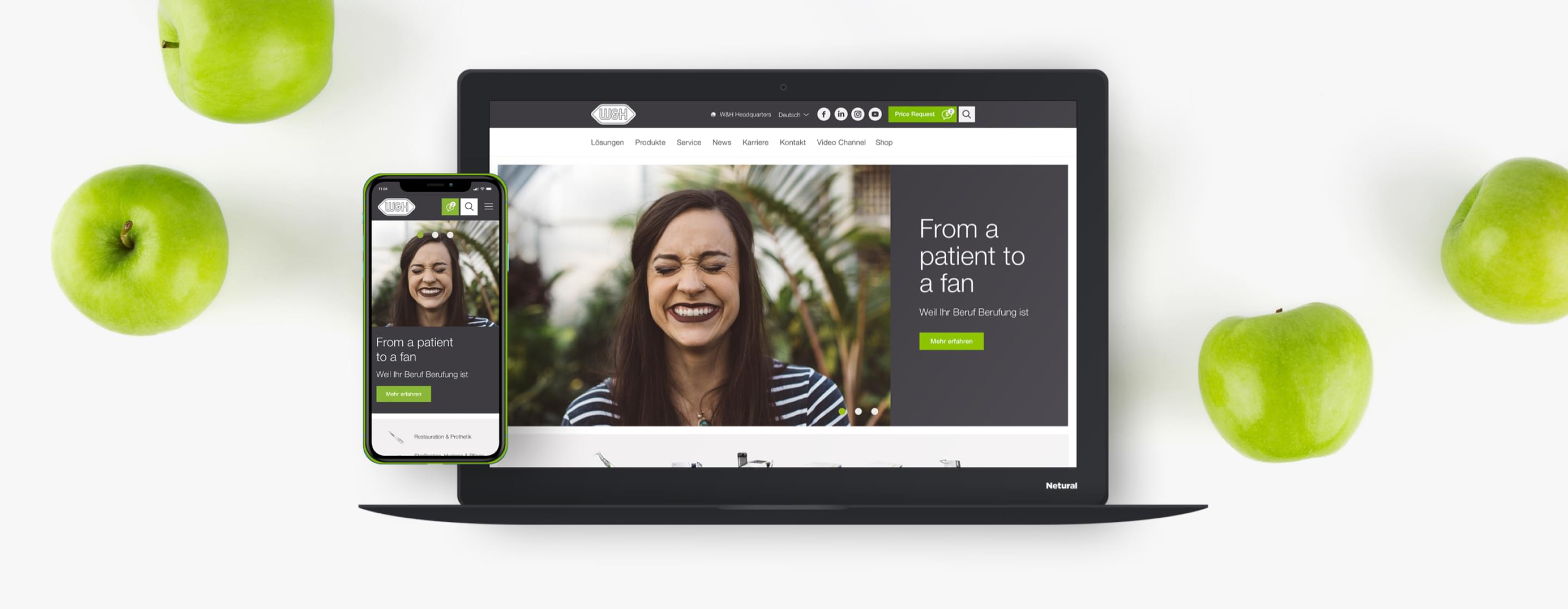 Monitor mit geöffneter W&H-Webseite, davor Lampe und Pflanze auf einem hellen Schreibtisch.