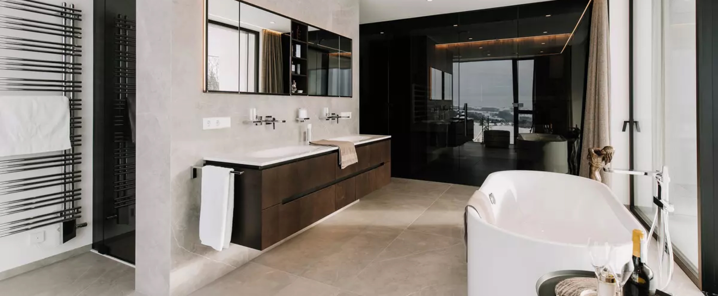 Einblick in ein offenes, modernes Badezimmer mit freistehender Badewanne und Fensterwand.