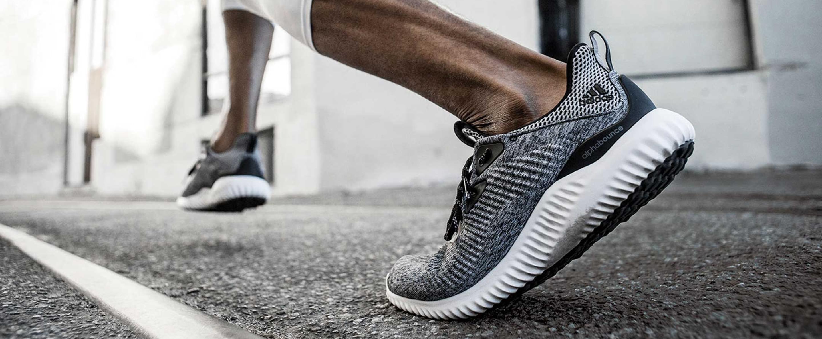 Nahaufnahme von den Beinen eines Läufers in Bewegung, die Person trägt graue Adidas Schuhe.