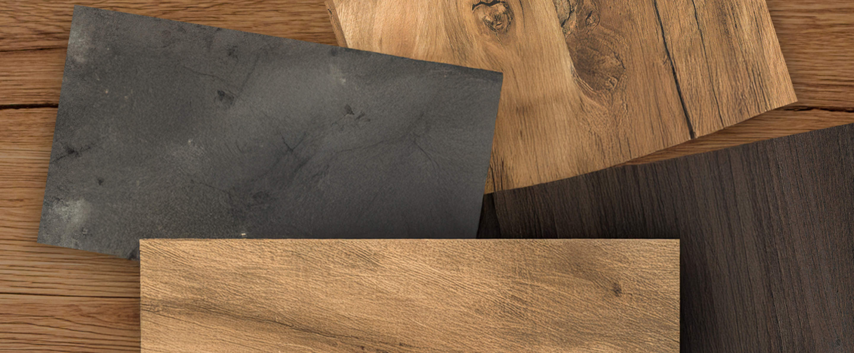 Nahaufnahme von vier Holz- und Steindekorplatten in verschiedenen Farb- und Strukturvarianten auf Holzuntergrund.