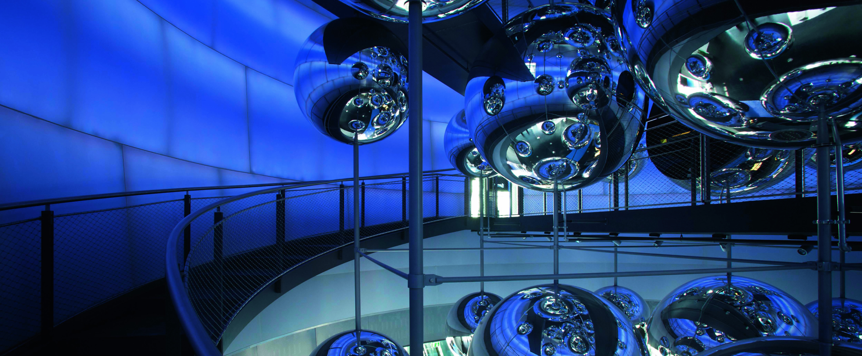 Spiegelnde Metallkugeln und blaue LED-Wände in der modernen Ausstellung voestalpine Stahlwelt