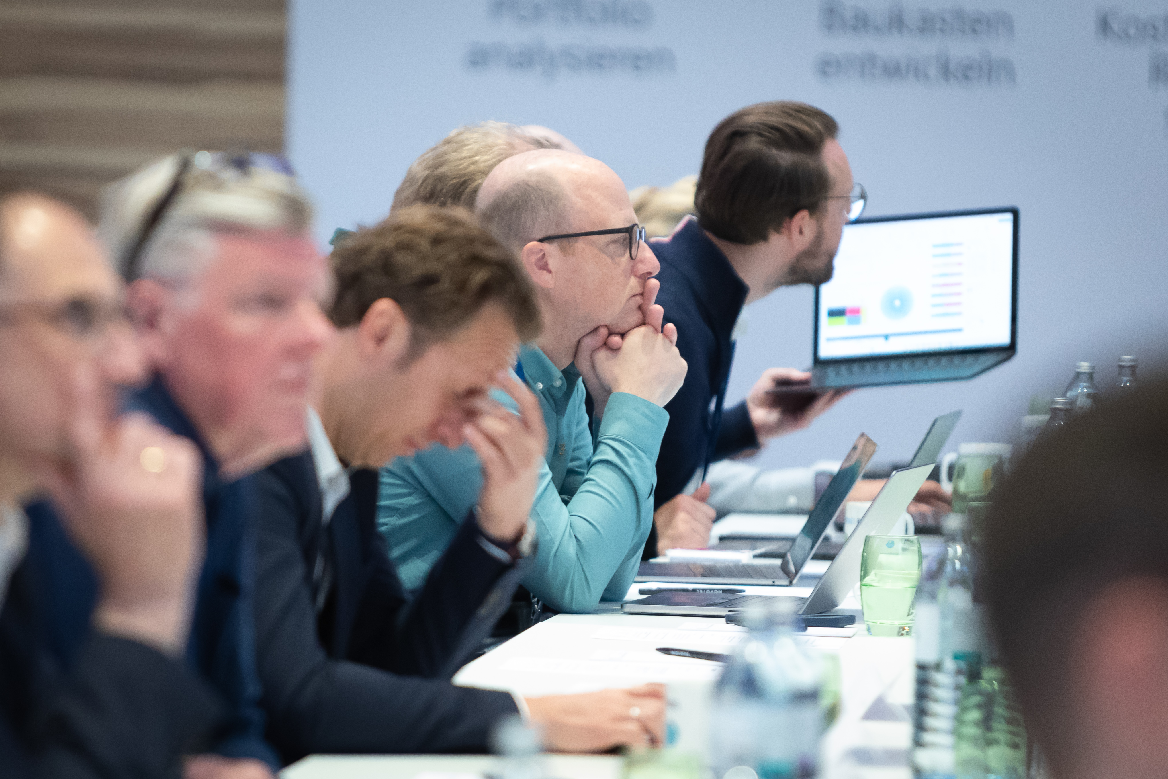 Männer mit Laptops folgen konzentriert einer Präsentation