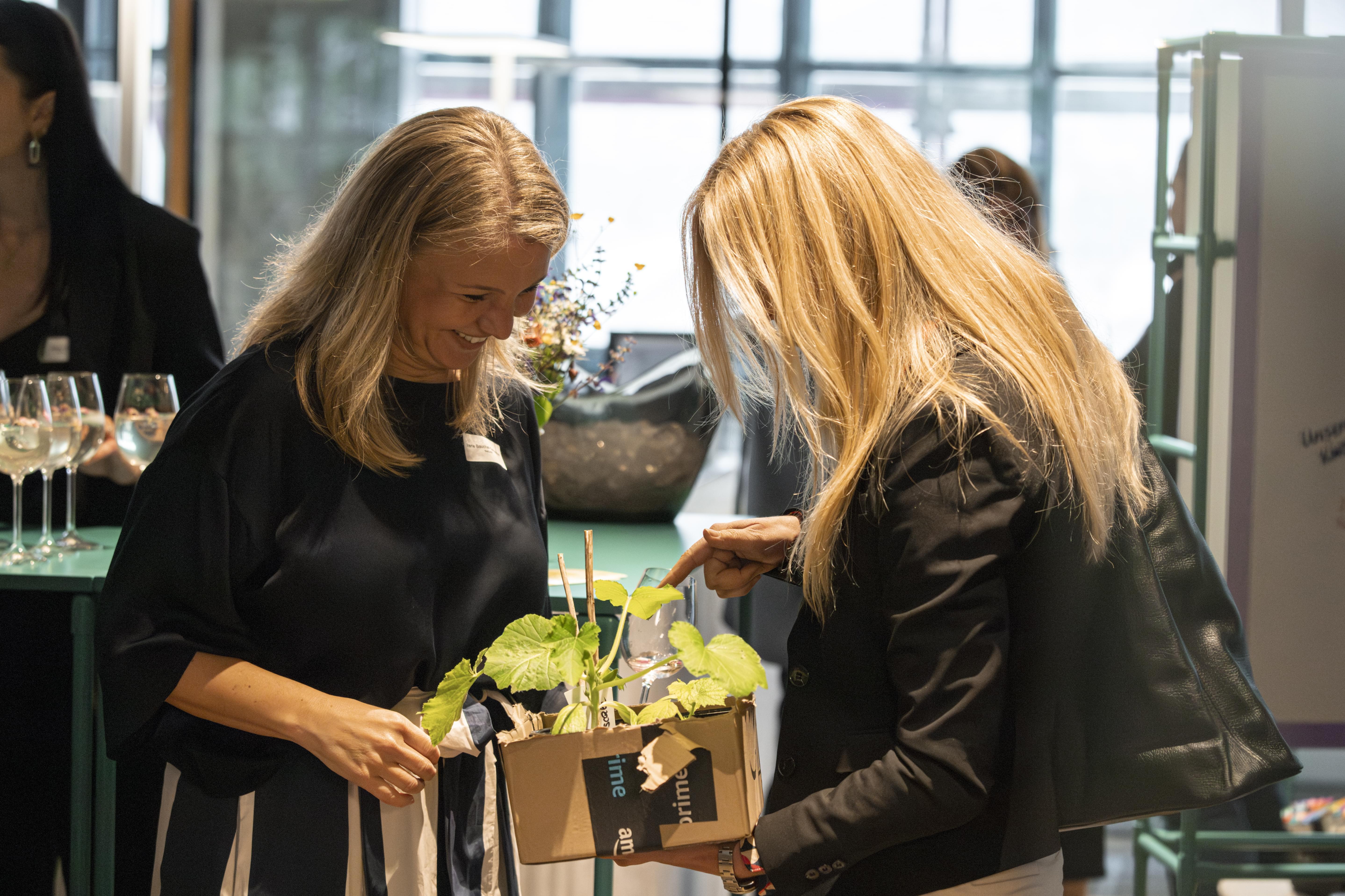 Zwei Frauen freuen sich über ein kleines Pflanzenpräsent in einer Geschenkbox bei der HR Coworking Night.