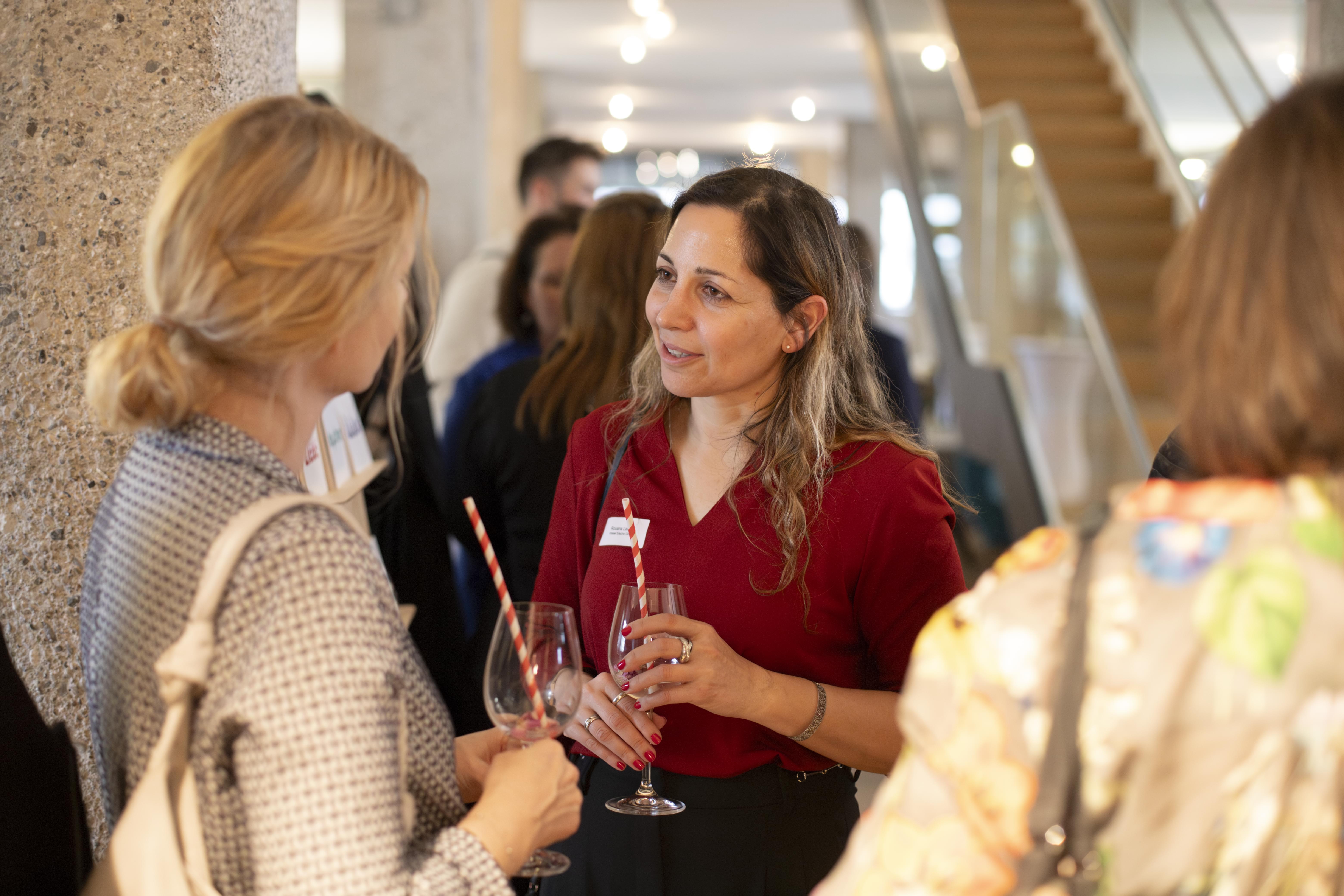 Zwei Frauen unterhalten sich bei der HR Coworking Night, beide mit Weinglas in der Hand.