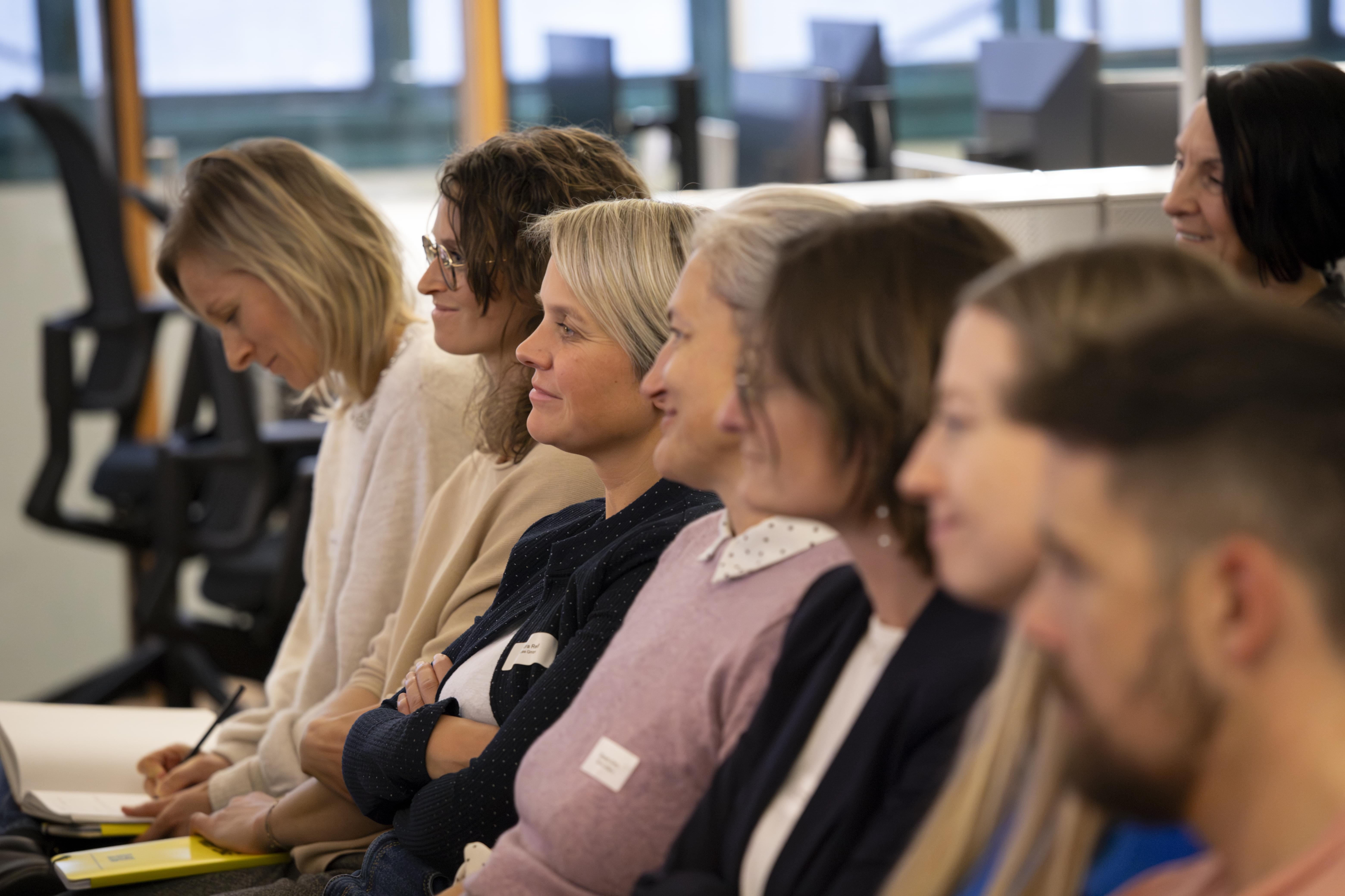 Gruppe von Frauen und Männern, die aufmerksam der Präsentation bei der HR Coworking Night lauschen.