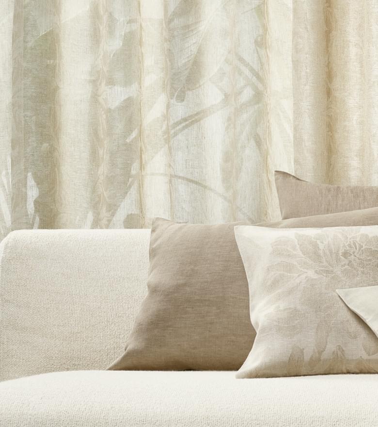 Beige Sofakissen mit floralen Mustern und Leinenstruktur.