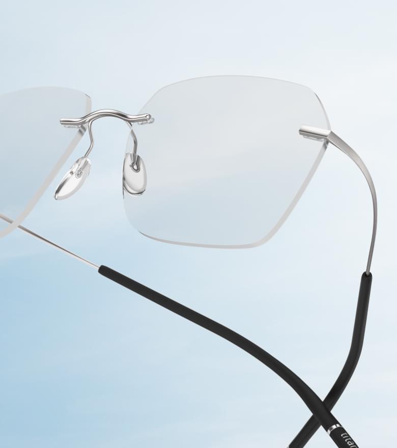 Eine moderne randlose Brille von Silhouette schwebt vor einem hellblauen Himmel.