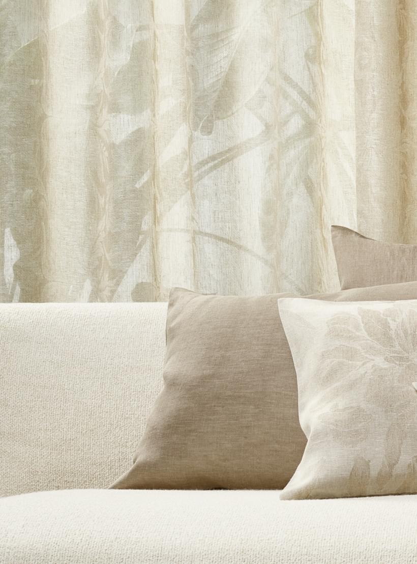 Beige Sofakissen mit floralen Mustern und Leinenstruktur.