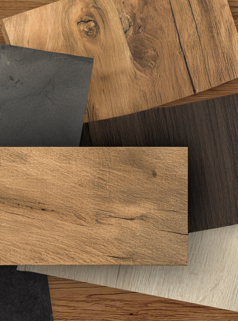 Nahaufnahme von vier Holz- und Steindekorplatten in verschiedenen Farb- und Strukturvarianten auf Holzuntergrund.