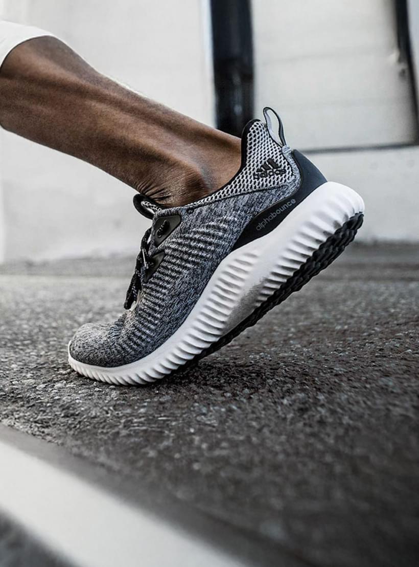 Nahaufnahme von den Beinen eines Läufers in Bewegung, die Person trägt graue Adidas Schuhe.