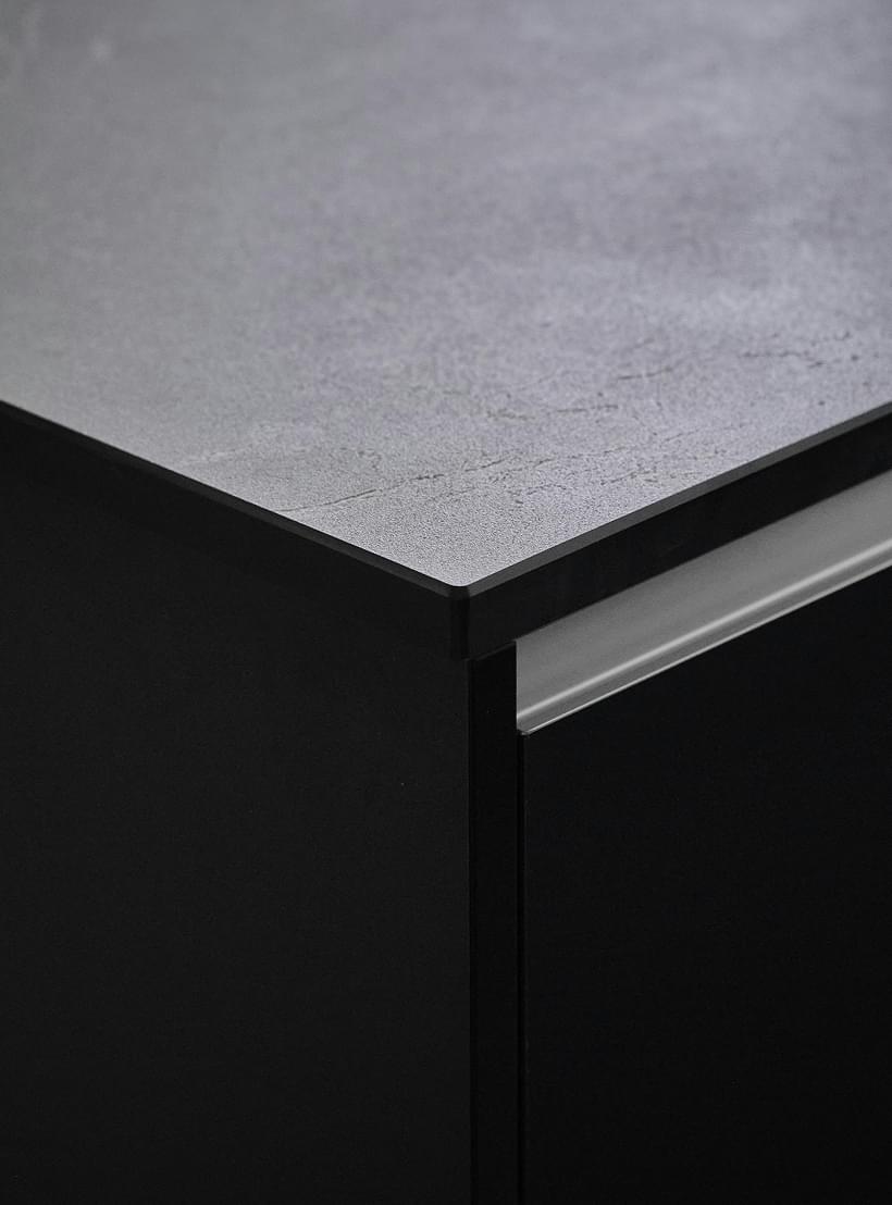 Detailaufnahme einer modernen Küchenarbeitsplatte mit dunkler, matter Oberfläche und klarer Linienführung.