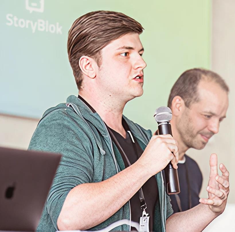 Dominik Angerer (CEO Storyblok) spricht vor einer Leinwand über Storyblok, im Hintergrund steht Albert Ortig (CEO Netural).