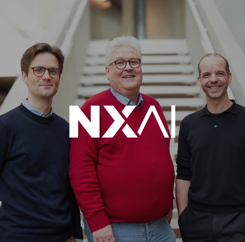 Neusser, Hochreiter und Ortig stehen lächelnd vor einer Treppe in moderner Architektur.